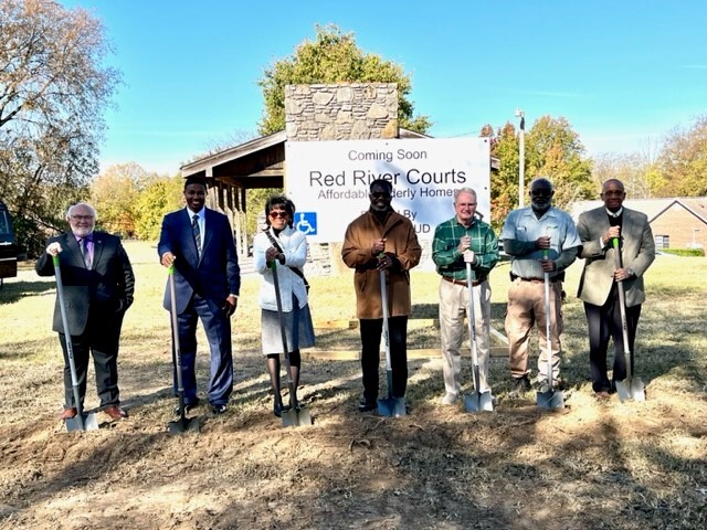 Individuals standing in line holding shovels.